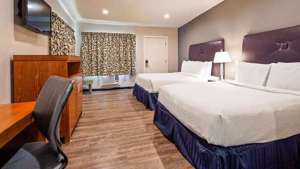A hotel room with two beds, a desk, a chair, a TV, and a patterned curtain. - Motel 6 Ridgecrest, CA - China Lake (Ridgecrest)