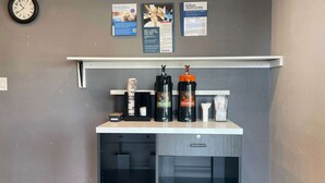 A coffee station with two coffee dispensers, a clock, and informational posters on the wall. - Motel 6 Ridgecrest, CA - China Lake (Ridgecrest)