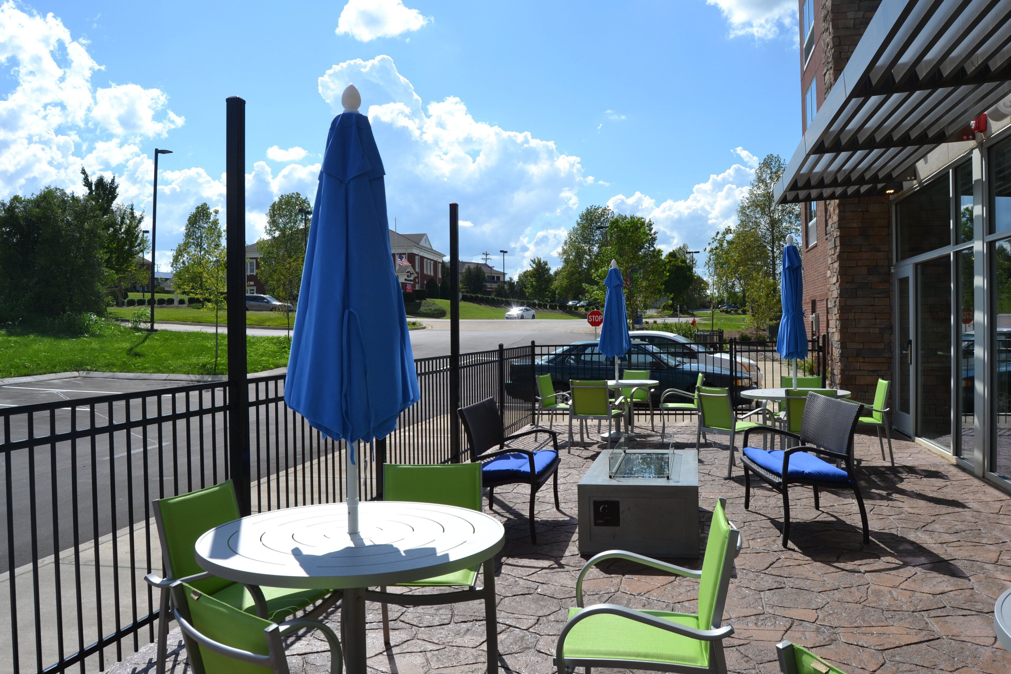 An outdoor patio with tables and chairs, a stop sign, and a building in the background.