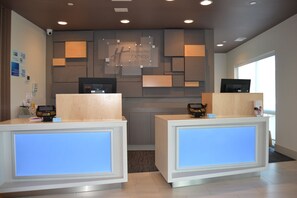 A reception desk area with two counters, a digital display, and a wall-mounted sign indicating a Holiday Inn Express & Suites. - Holiday Inn Express & Suites Goodlettsville N - Nashville by IHG (Goodlettsville)