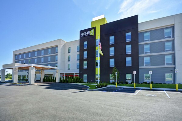 A modern hotel with a prominent 'HOME 2' sign, multiple floors, and a covered parking area.