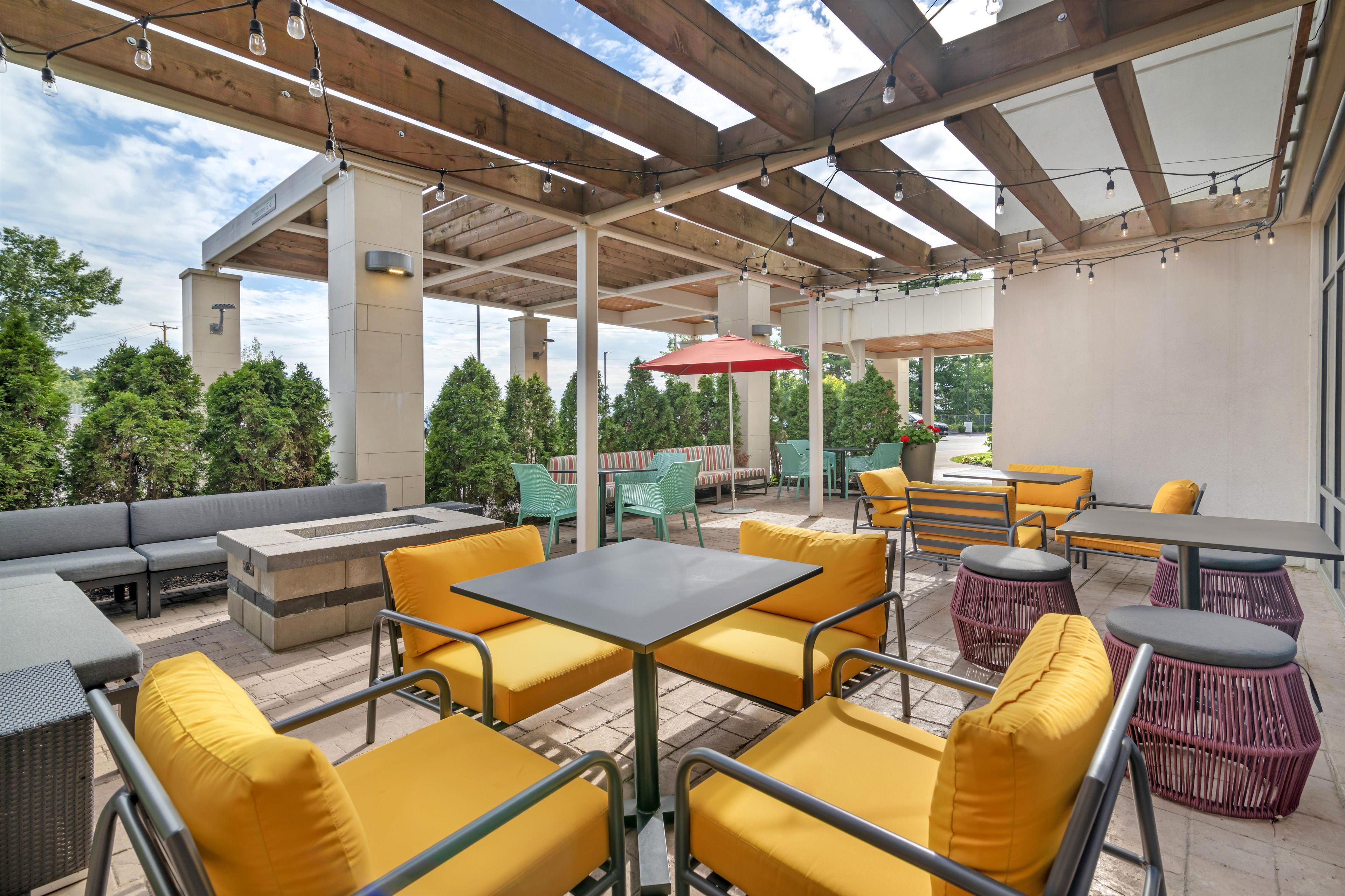 An outdoor patio with seating arrangements, a fire pit, and a pergola structure.