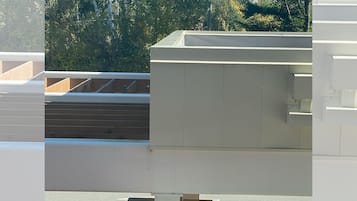 Een modern gebouw met een plat dak, betonnen constructies en een verhard gebied met kleine planten.