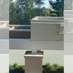 Ein modernes Gebäude mit flachem Dach, Betonkonstruktionen und einer gepflasterten Fläche mit kleinen Pflanzen.