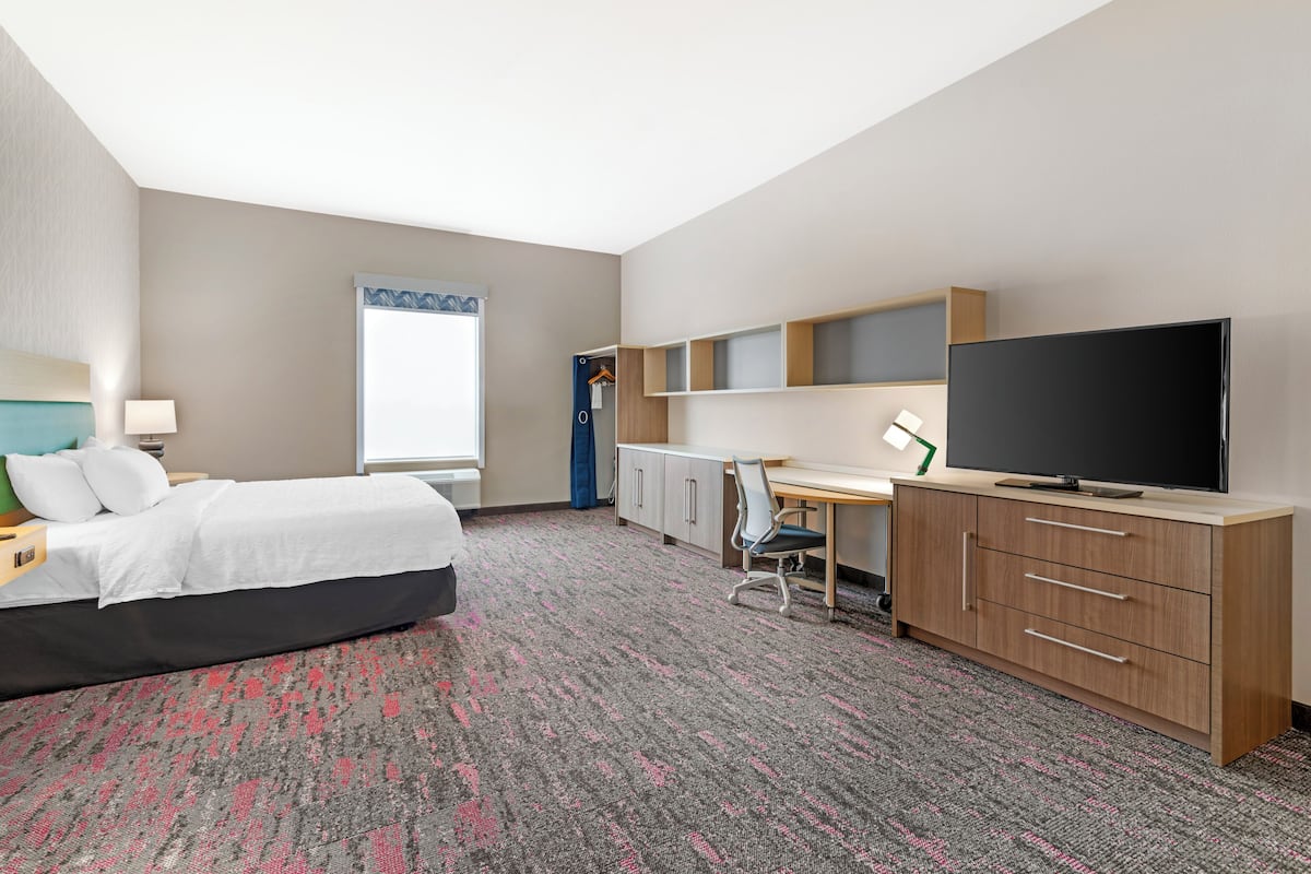 Een hotelkamer met een bed, bureau, televisie en kledingkast.