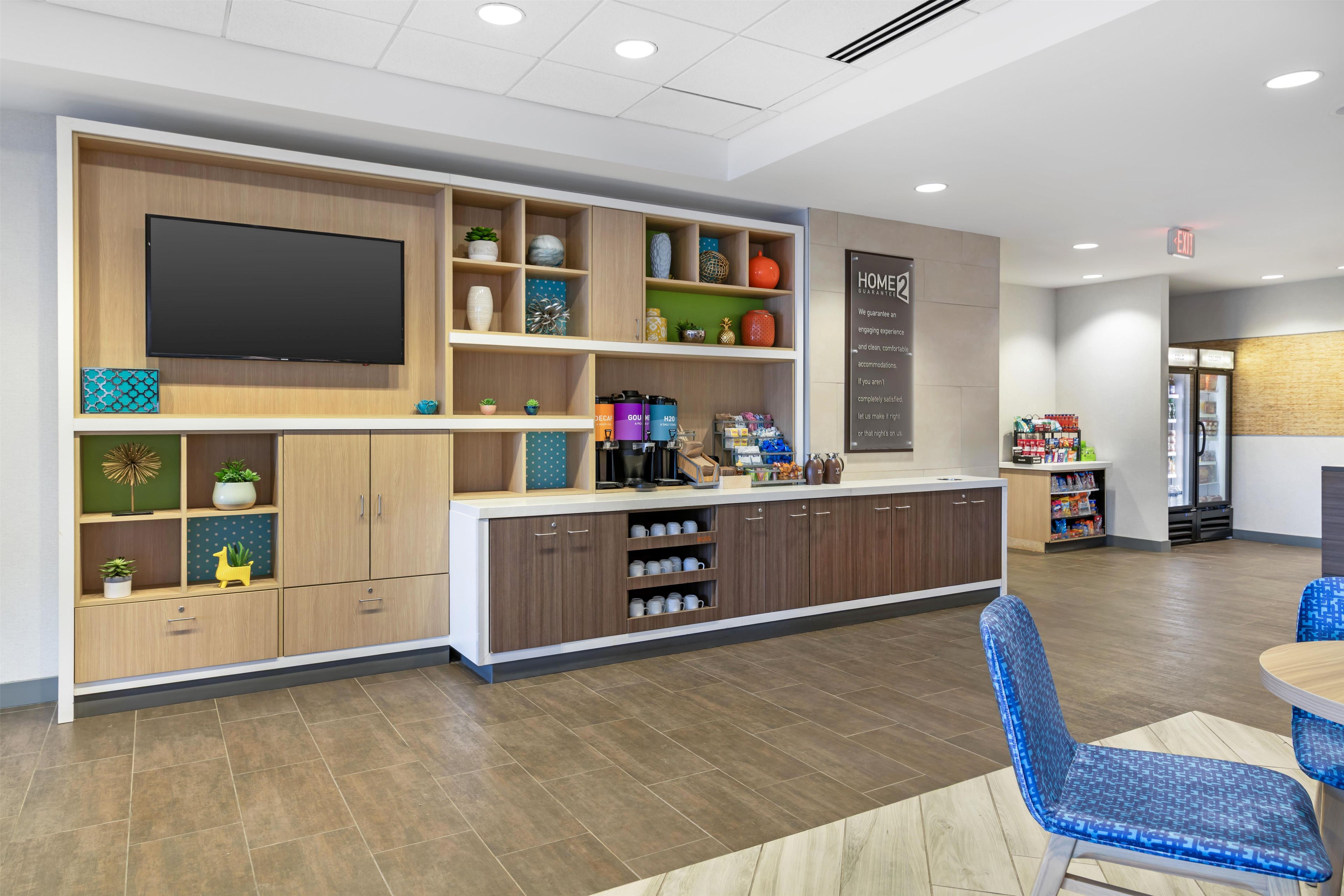 A modern kitchen area with a flat-screen TV, built-in cabinets, and a coffee station.