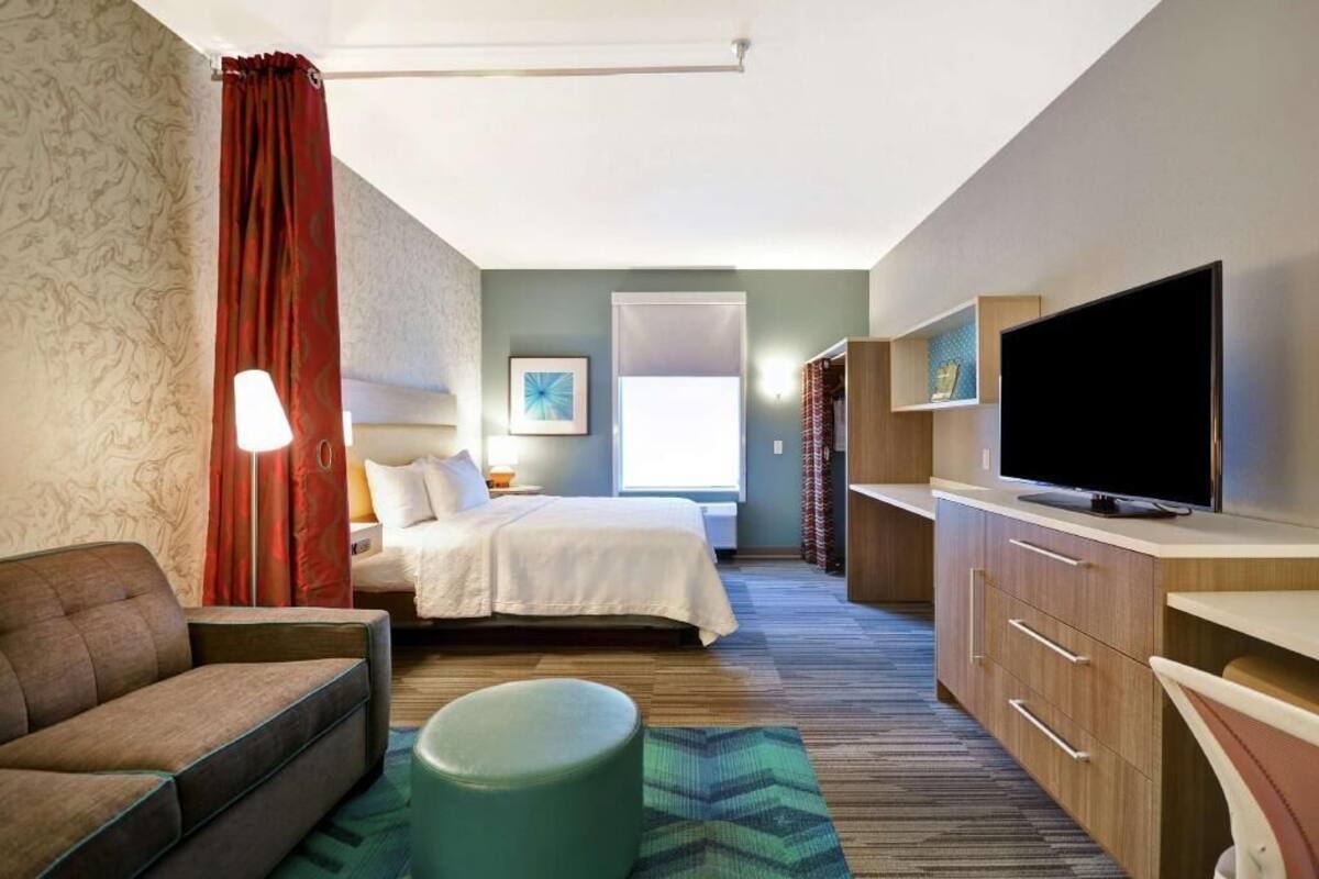 Een hotelkamer met een bed, een bank, een televisie, een bureau en een raam.