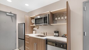 A modern kitchen with a built-in microwave, coffee maker, and dishwasher. - Home2 Suites by Hilton Queensbury Lake George (Queensbury)