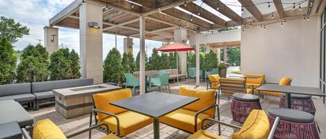 Una terrazza esterna con posti a sedere, un braciere e una struttura a pergola.