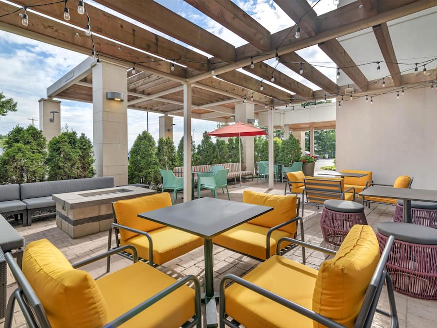 An outdoor patio with seating arrangements, a fire pit, and a pergola structure.