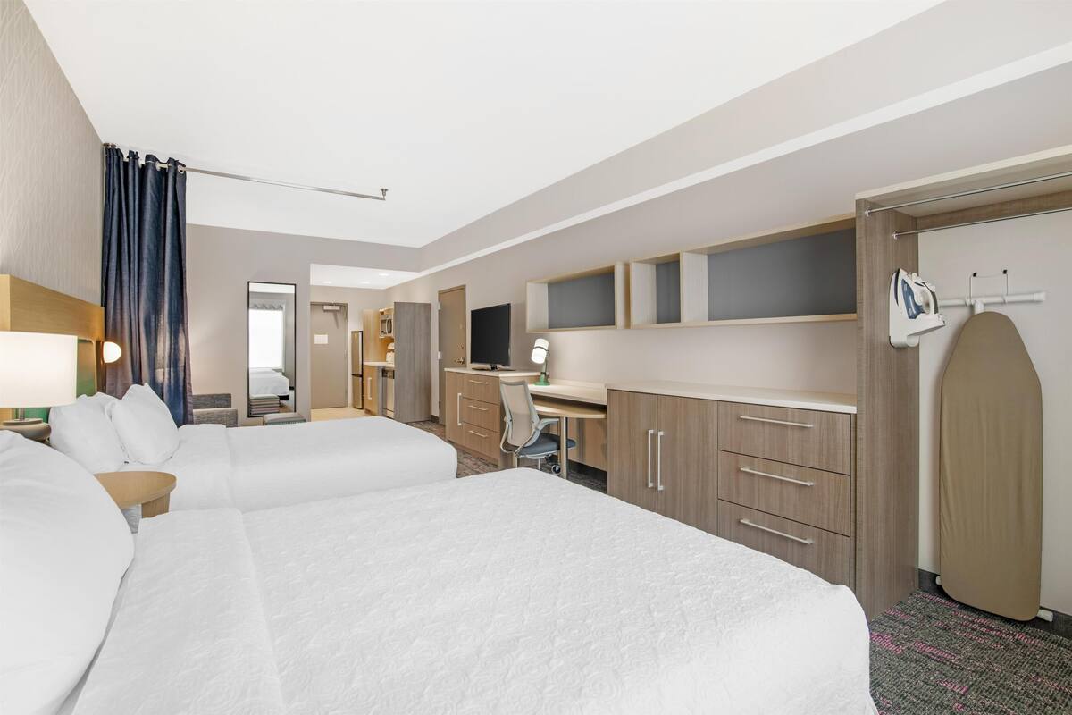 Hotelkamer met twee bedden, een bureau, een stoel, een televisie, een kledingkast en een badkamer.