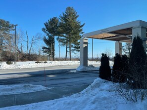 A gas station with a covered canopy, snow on the ground, and trees in the background.