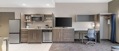 A modern kitchen with built-in appliances, a dining area, and a workspace with a desk and chair.