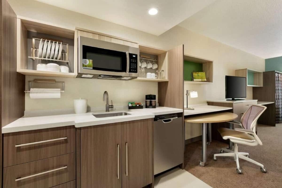 A compact kitchenette with a microwave, sink, and built-in oven.