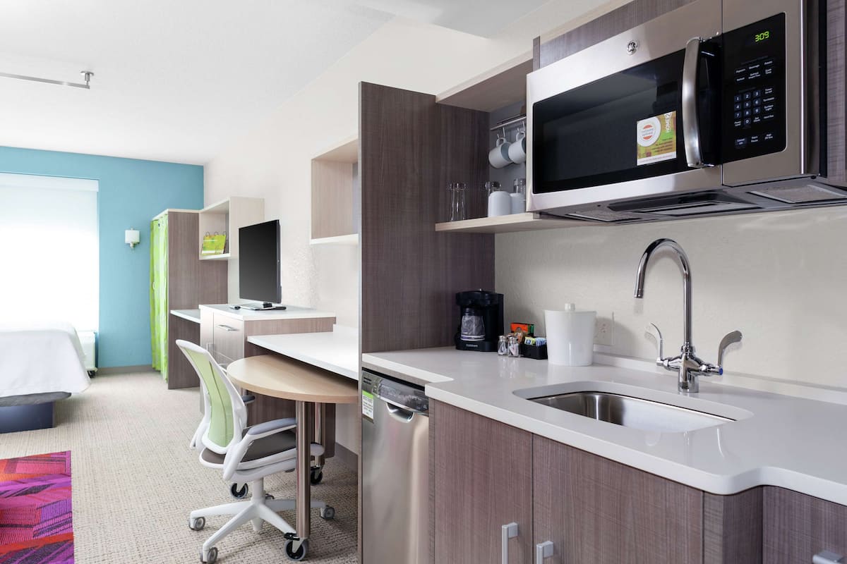 A compact hotel room with a kitchenette, including a microwave, coffee maker, and sink.