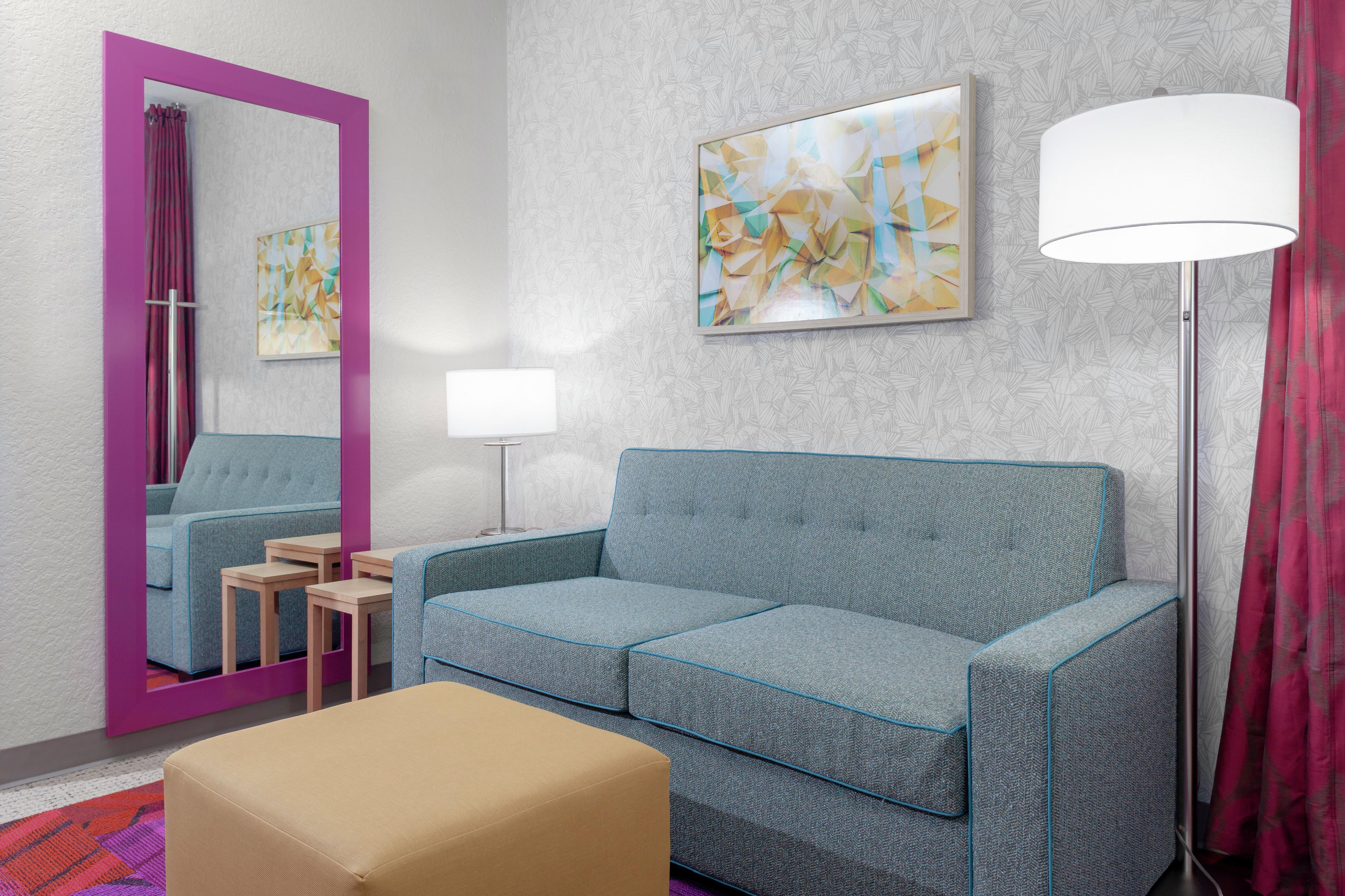 Una habitación moderna con sofá, una mesita, una lámpara y un espejo.