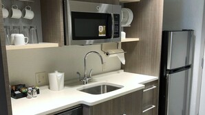A modern kitchen with a built-in dishwasher, stainless steel appliances, and a sleek design. - Home2 Suites by Hilton Orlando South Park (Orlando)