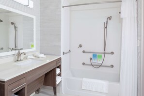 Un baño moderno con tocador doble, ducha a ras de suelo con barras de apoyo y un perchero para toallas.