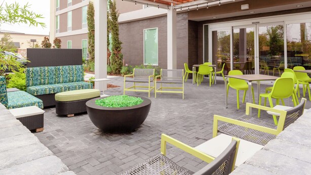 An outdoor seating area with wicker furniture and a large planter. - Home2 Suites by Hilton Orlando South Park (Orlando)