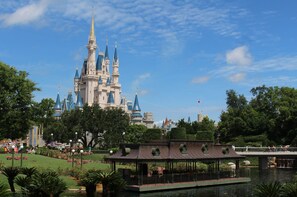 A castle-like structure with multiple spires and a large flag, surrounded by lush greenery and a body of water with a boat dock. - Home2 Suites by Hilton Orlando South Park (Orlando)