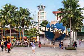 A large globe with the word "UNIVERSAL" in front of a building with palm trees and people around. - Home2 Suites by Hilton Orlando South Park (Orlando)