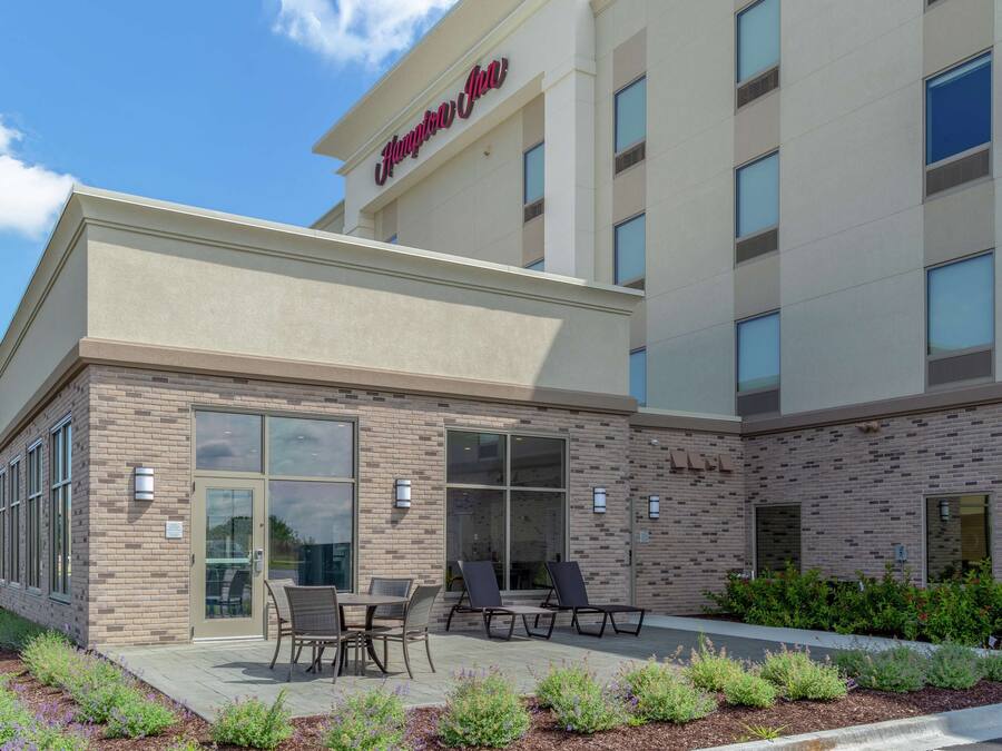 A hotel exterior with a brick facade, large windows, and outdoor seating area.