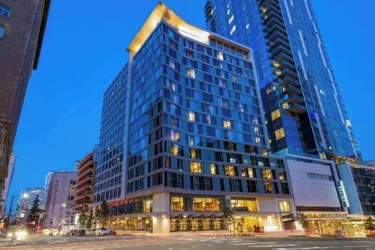 A multi-story hotel with a modern glass facade, large windows, and a corner entrance.