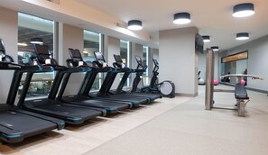 A gym with multiple treadmills, exercise bikes, and a rowing machine. - The Charter Hotel Seattle, Curio Collection by Hilton (Seattle)