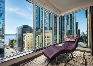 A modern room with large windows, a leather chair, and a view of the cityscape. - The Charter Hotel Seattle, Curio Collection by Hilton (Seattle)