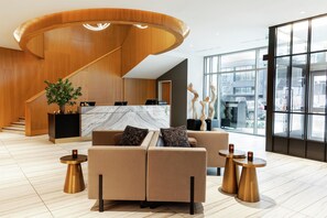 A modern lobby with a curved reception desk, seating area with sofas, and a large window offering a view of the city. - The Charter Hotel Seattle, Curio Collection by Hilton (Seattle)
