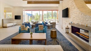A spacious living area with a fireplace, comfortable seating, and large windows offering a view of the outdoors. - Residence Inn by Marriott Phoenix Chandler/South (Chandler)