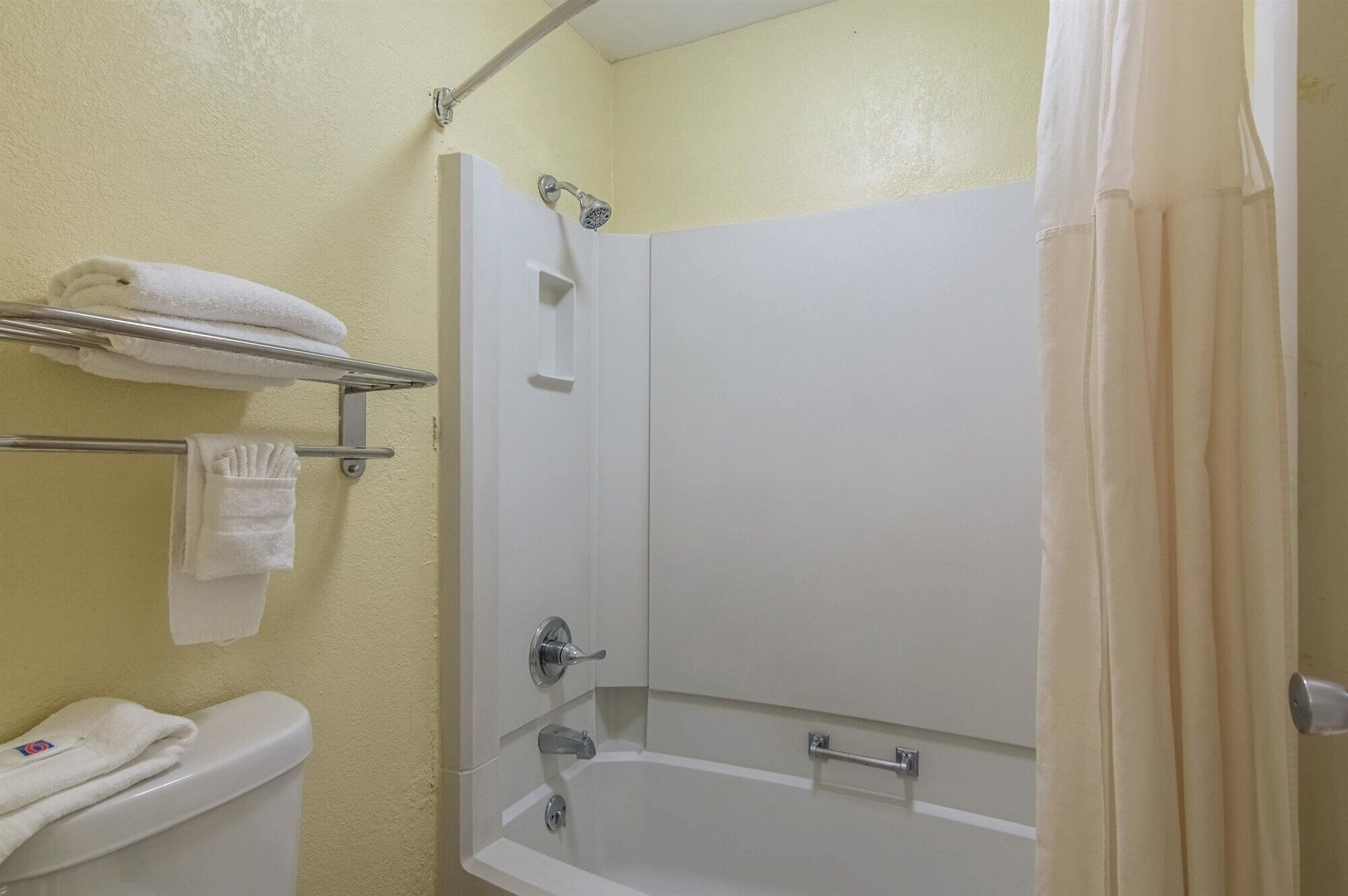 Un baño con bañera, inodoro y toallero con toallas.