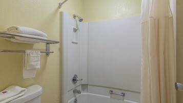 Un baño con bañera, inodoro y toallero con toallas.
