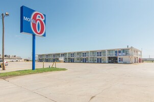 Un motel con un letrero grande, un estacionamiento y un edificio con varias habitaciones.