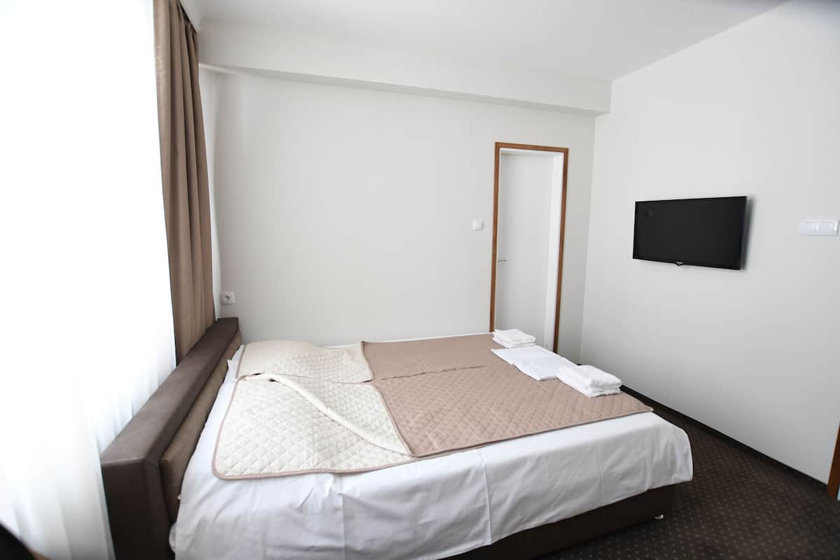 Quarto de hotel com uma cama, televisão e uma porta.