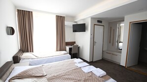 Une chambre d’hôtel avec deux lits, un bureau, une télévision et une armoire.