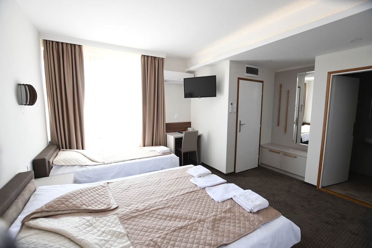 Quarto de hotel com duas camas, uma escrivaninha, uma televisão e um guarda-roupa.