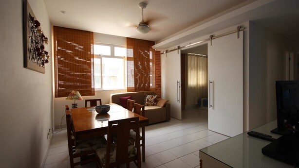 Un'area pranzo con un tavolo e sedie in legno, un divano e una TV su un tavolino in vetro.