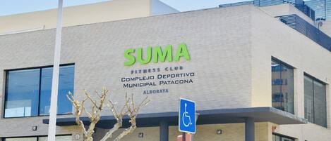 A building with a sign reading "SUMA FITNESS CLUB" and a handicapped accessibility sign.
