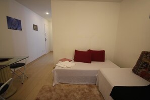 A small, well-lit room with a bed, a desk, and a chair. There are two pillows on the bed and a small rug on the floor. - GoHouse Djalma 519 (Rio de Janeiro)