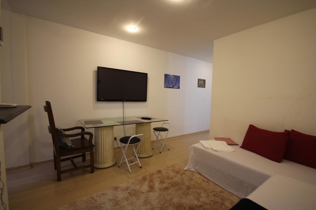 A bedroom with a bed, a desk, a chair, a television, and a small rug.