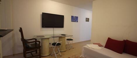 A bedroom with a bed, a desk, a chair, a television, and a small rug.