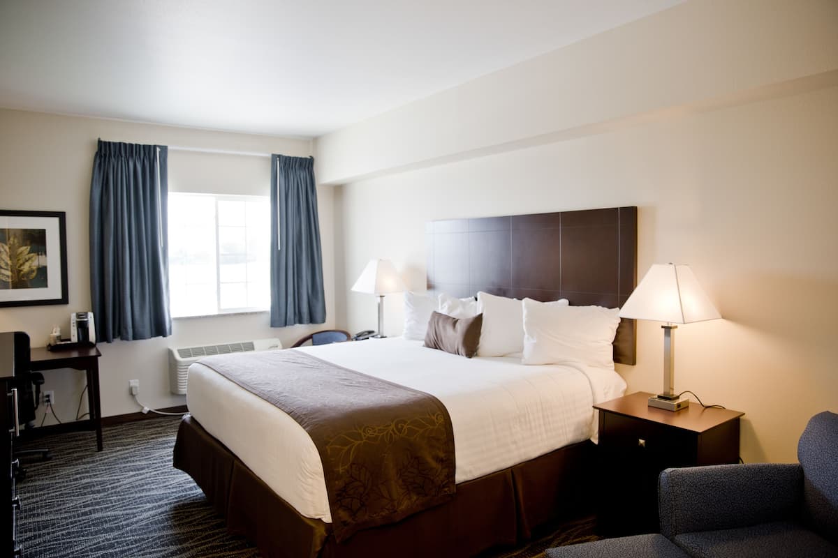 A hotel room with a large bed, two bedside lamps, a desk, and a chair.