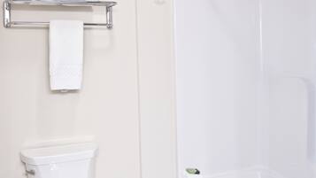Un baño con inodoro, ducha y un perchero con toallas dobladas.