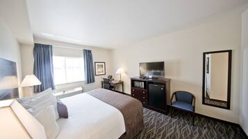 A hotel room with a bed, desk, chair, TV, and a large mirror.