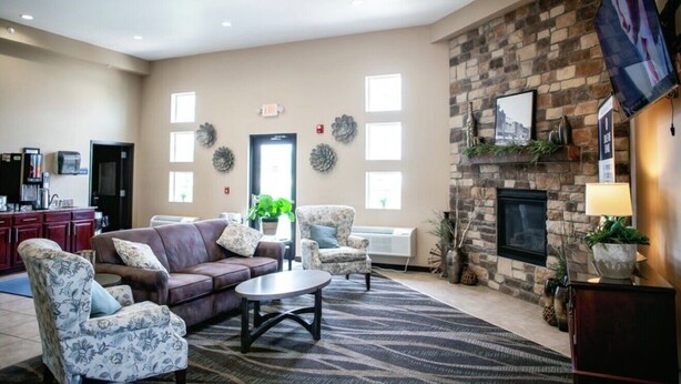 A spacious lobby with a fireplace, seating area, and a television mounted on the wall. - Cobblestone Inn & Suites - Clarinda (Clarinda)