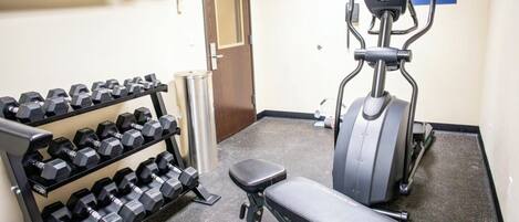A gym with dumbbells, a bench, and a stationary bike.