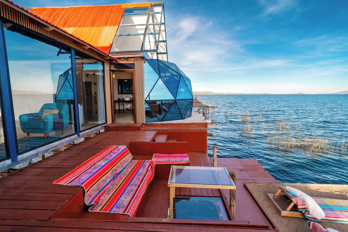A modern boat with a glass-enclosed deck, wooden furniture, and a view of the sea.