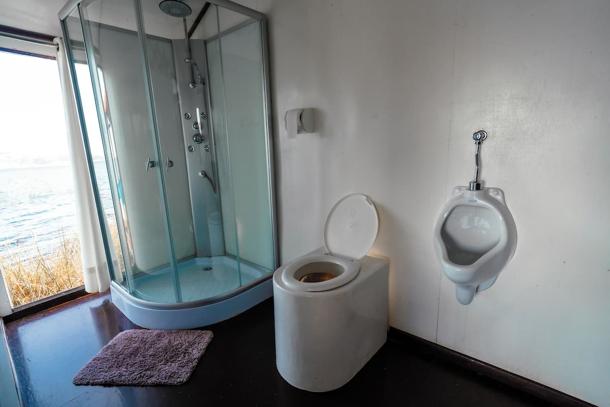 A bathroom with a glass-enclosed shower, a white toilet, and a urinal mounted on the wall.