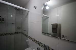 A modern bathroom with a glass shower enclosure, a large mirror, and a towel rack.